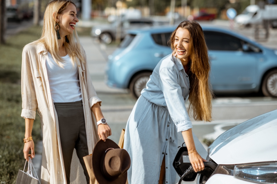 שתי נשים נהנות להטעין רכב חשמלי.