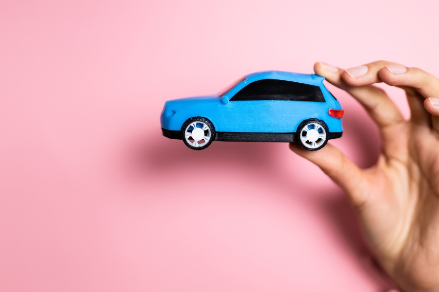 יד מחזיקה רכב צעצוע קטן בצבע כחול.